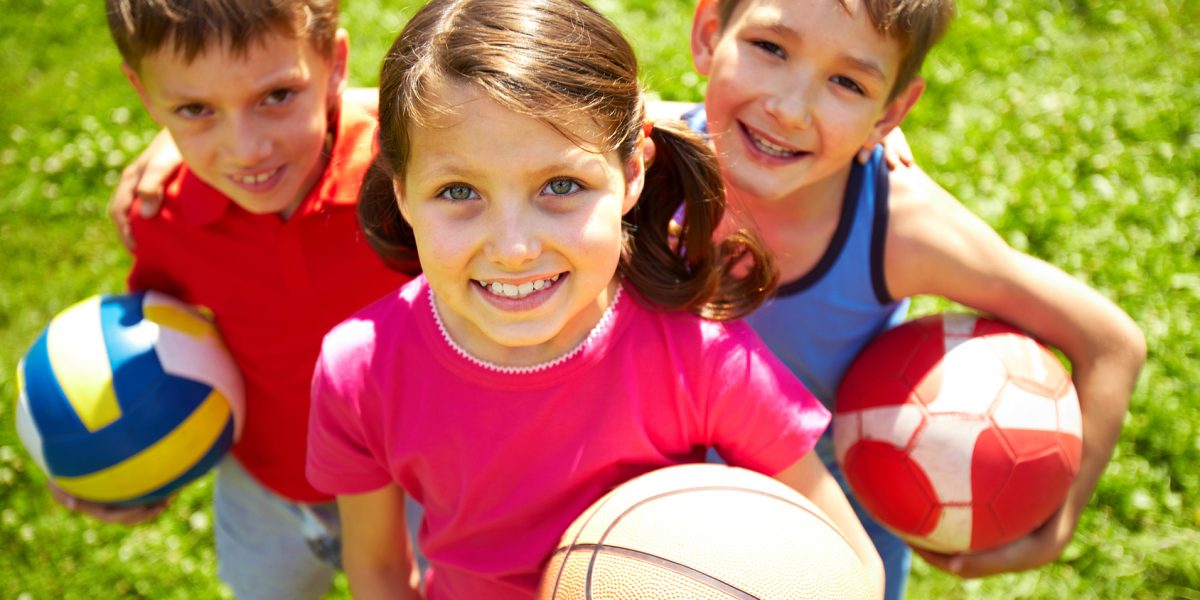 Portrait of three little children with balls looking at camera and smiling